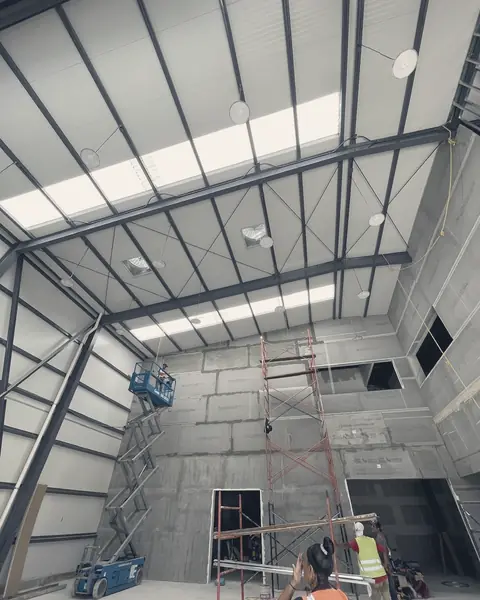 Interior de la nave de un hangar con andamios y plataforma de elevación durante la obra