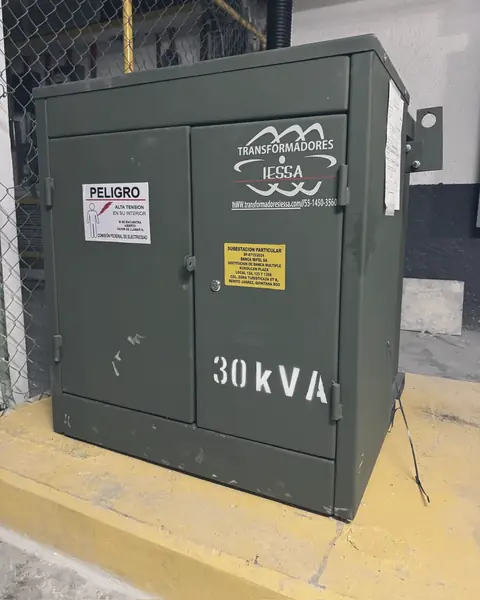 Transformador tipo pedestal de 30 kVA sobre base amarilla en un sótano
