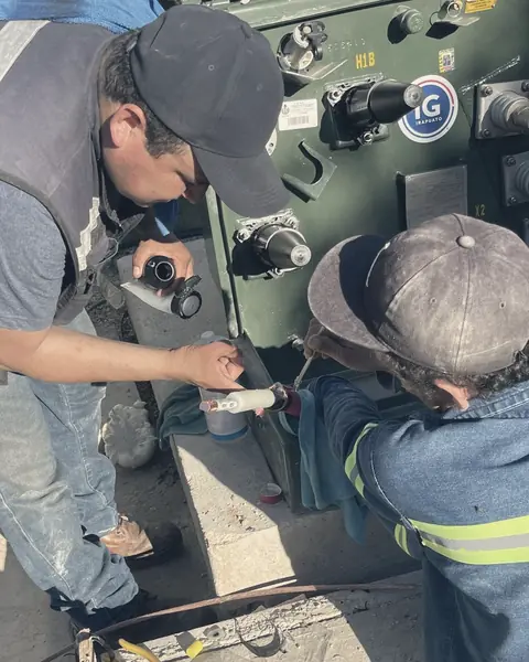 Dos técnicos conectan los codos de media tensión del transformador